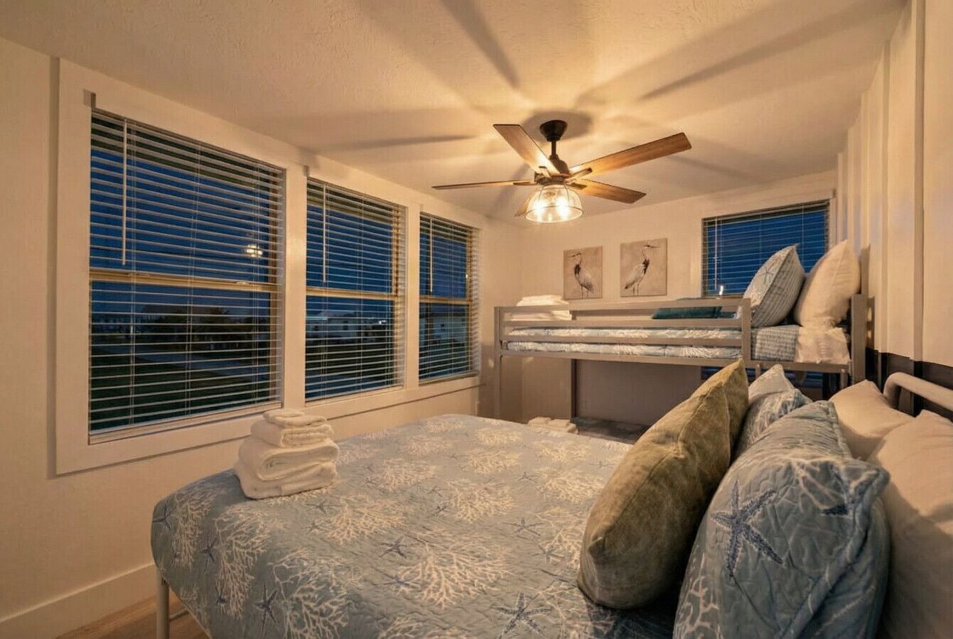 Un dormitorio con cama, ventilador de techo y ventana con persianas.