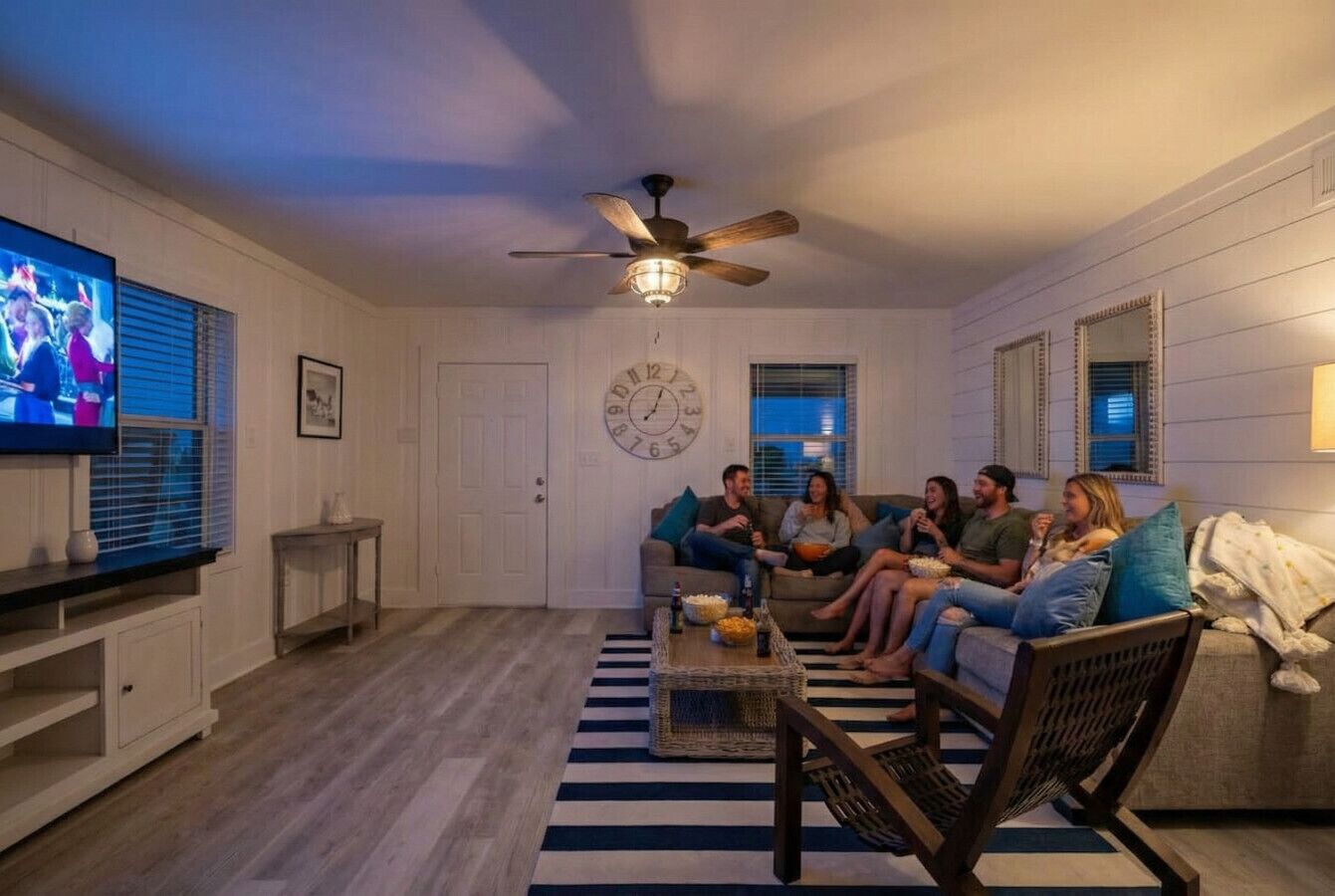 Ein Wohnzimmer mit Fernseher, Deckenventilator und einer Uhr an der Wand.