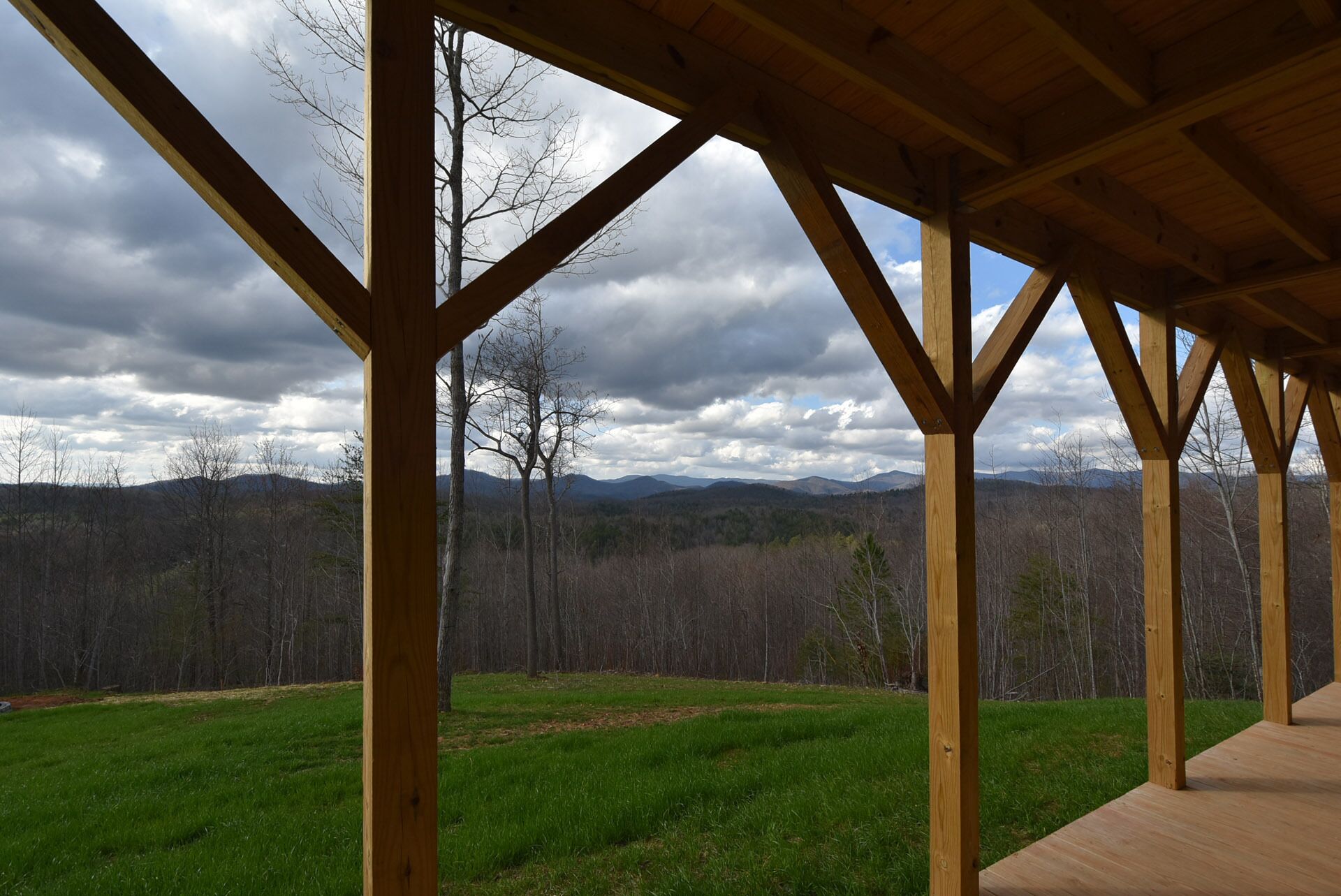 A covered outdoor area with a view of a forest and mountains.