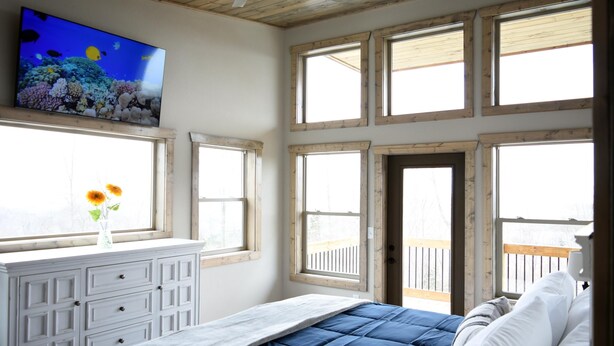 Una camera da letto con un letto, una TV a parete e diverse finestre.