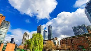 Un paysage urbain comprenant des bâtiments modernes et historiques, notamment un imposant gratte-ciel en verre et un bâtiment en briques doté de grandes fenêtres.