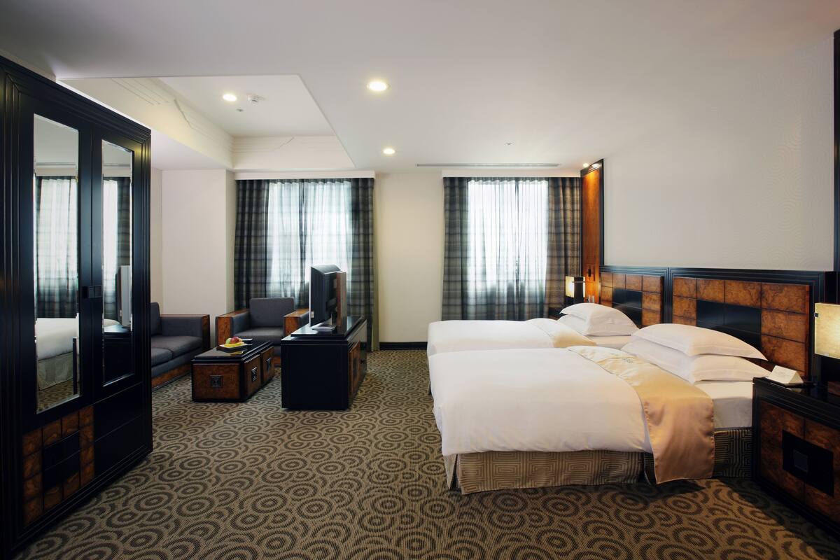 Una habitación de hotel con una cama grande, un sofá, un escritorio con televisor y un espejo.