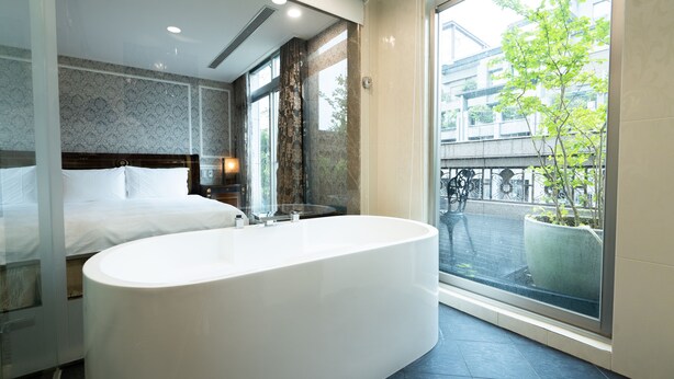 Un baño moderno con una bañera independiente grande, una zona de ducha separada y un amplio ventanal con vistas a la ciudad.