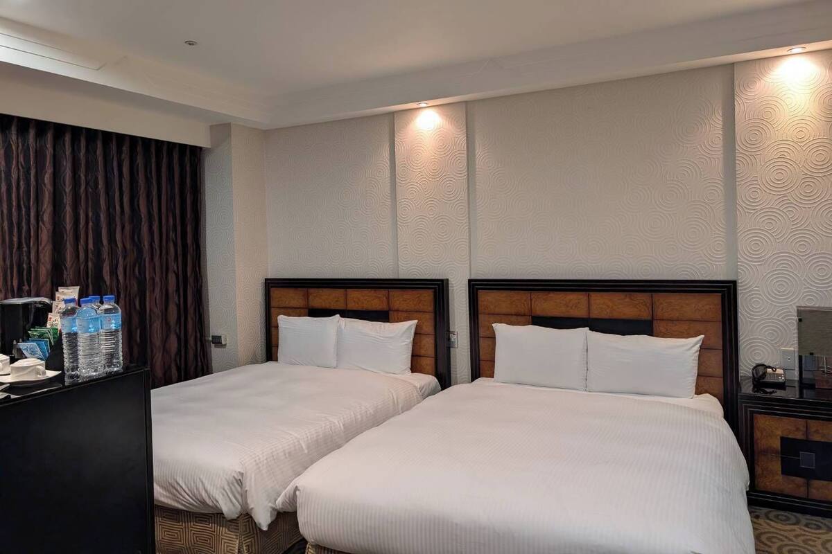 Habitación de hotel con dos camas, un minibar y un televisor.
