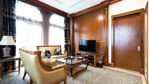 Habitación de hotel elegante con sofá de cuero, una mesa de centro de vidrio, televisor de pantalla plana y armario de madera.