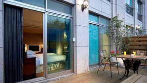 Habitación de hotel con un amplio ventanal corredero, una cama, una mesita de noche y una ventana.