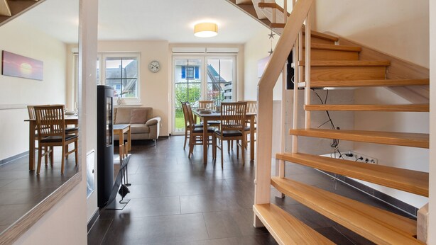 Un intérieur moderne avec un escalier, un coin repas et une vue sur l’extérieur.
