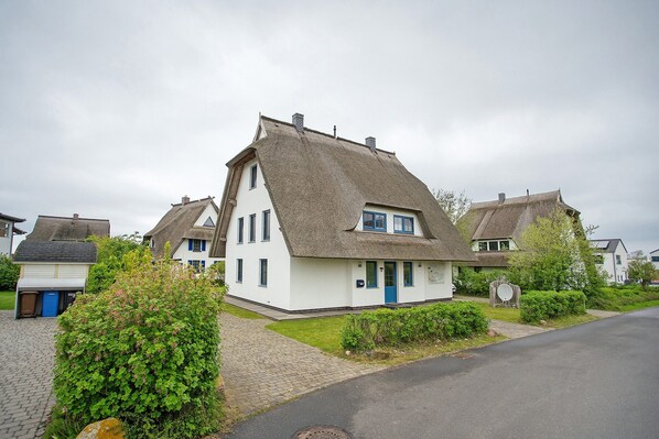 Une maison traditionnelle avec un toit à forte pente, une porte d’entrée et un petit porche.