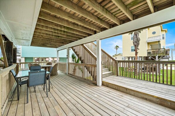 A wooden deck with a table and chairs, a staircase, and a view of a building.