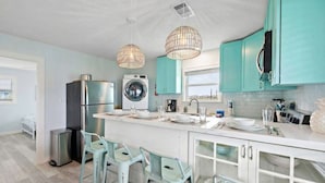 Una cocina moderna con una isla central, electrodomésticos de acero inoxidable y armarios color turquesa.