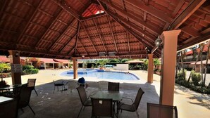 An outdoor pool area with a covered seating area and tables. - Newly Renovated Condo One Block From Beach (Buenos Aires)