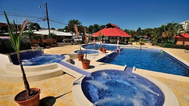 A swimming pool area with multiple hot tubs and potted plants. - Newly Renovated Condo One Block From Beach (Buenos Aires)