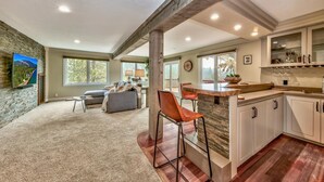 A spacious living area with a large window, a cozy seating area, and a kitchen with a bar.