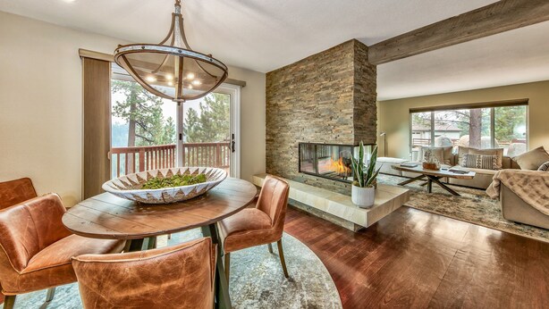 A modern living room with a fireplace, a dining area with a wooden table and leather chairs, and a stone accent wall.