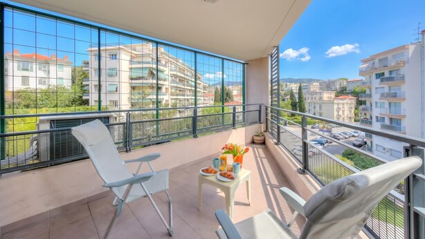 A balcony with a table, chairs, and a view of surrounding buildings. - Appartement Liberation 2, Nice, France (Nice)