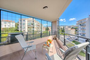 A balcony with a table, chairs, and a view of surrounding buildings.