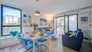 A modern living room with a dining area, large windows, and a view of a building. - Appartement Liberation 2, Nice, France (Nice)