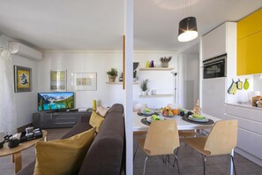 A modern living room with a sofa, TV, and a dining area with chairs and a table set for a meal. - Appartement Liberation 1, Nice, France (Nice)