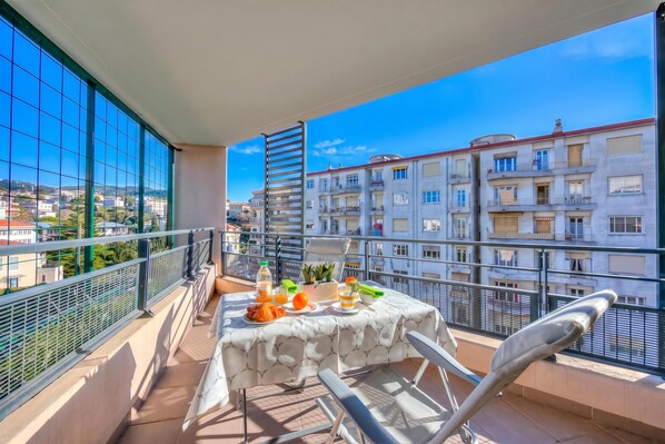 A balcony with a table set for breakfast, overlooking a cityscape.