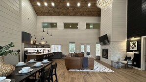 A spacious kitchen with a dining area, wooden floors, and a fireplace. - Stunning Modern Cabin (Broken Bow)
