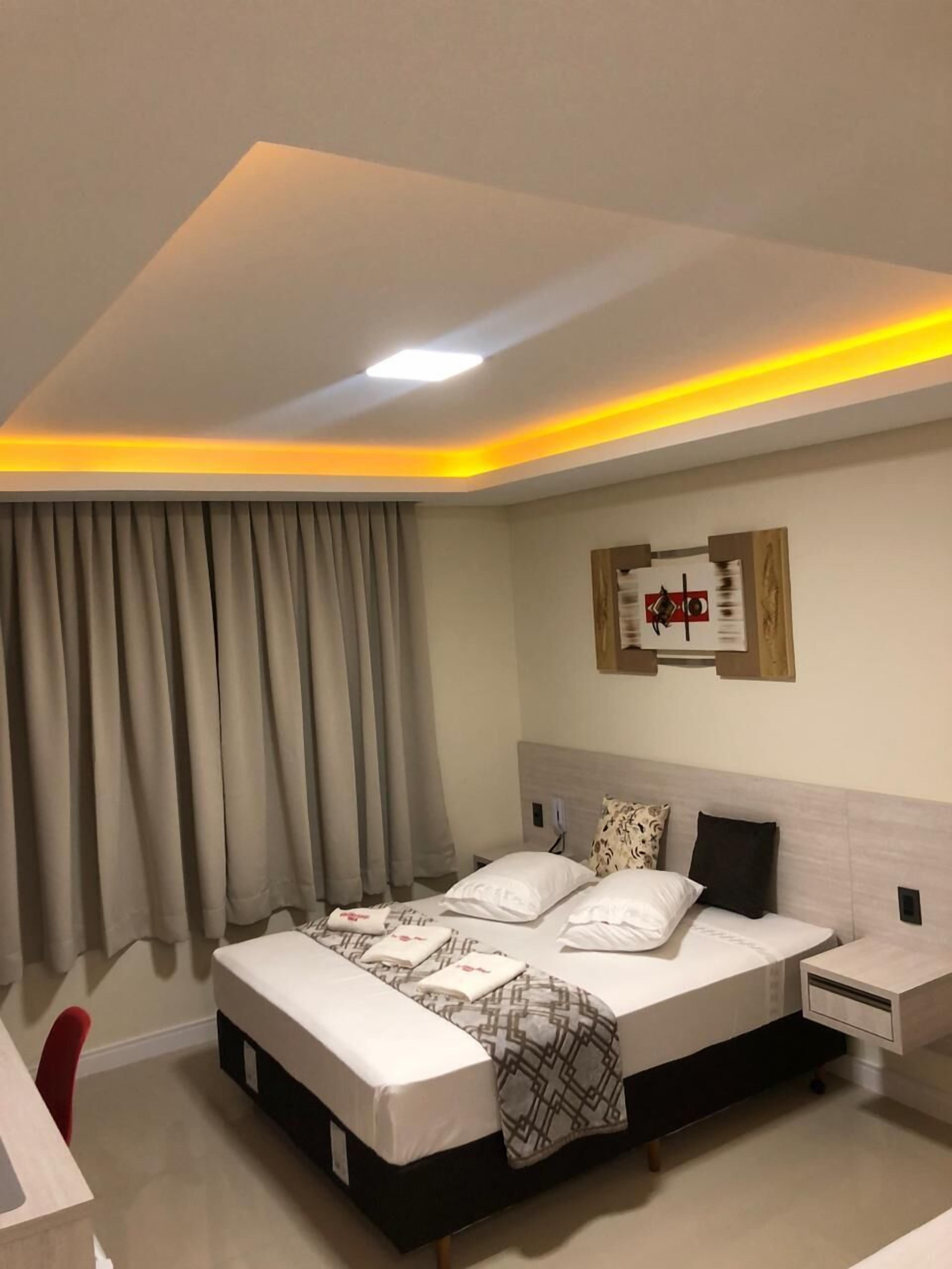 A modern bedroom with a large bed, bedside tables, and a ceiling light.