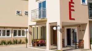 A two-story building with a balcony on the second floor, a visible entrance, and a parking area with cars. - Hotel Balneário do Parque (Penha)