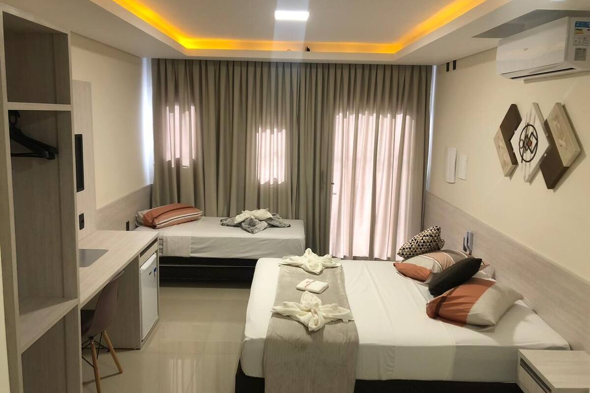 A hotel room with two beds, a desk, and a wardrobe.