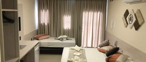 A hotel room with two beds, a desk, and a wardrobe.