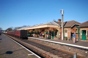 A train station platform with a brick building, a clock, and a green door.