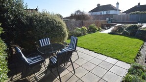 A patio with a table and chairs, a well-maintained lawn, and a wooden fence.