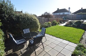 A patio with a table and chairs, a well-maintained lawn, and a wooden fence.