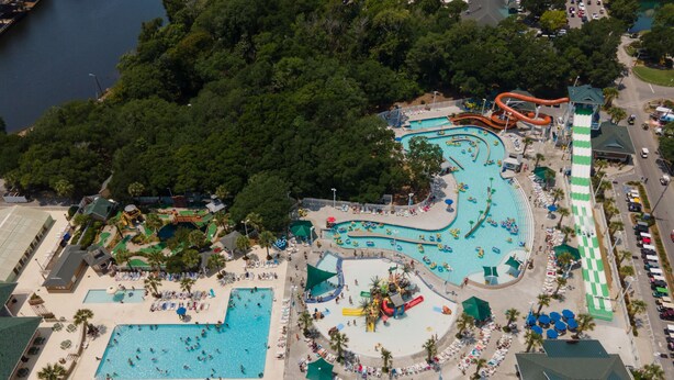 Vista aérea de um parque aquático com várias piscinas, uma piscina de ondas e um toboágua grande.