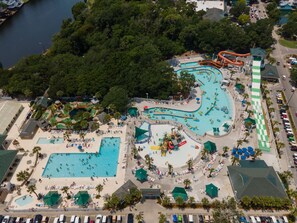 Vista aérea de um parque aquático com várias piscinas, uma piscina de ondas e um toboágua grande.