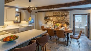 Une cuisine moderne dotée d’un grand îlot central, d’un revêtement de sol en pierre et de poutres apparentes en bois.