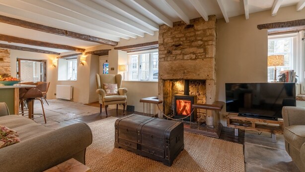 Un salon chaleureux avec une cheminée en pierre, des fauteuils confortables et un téléviseur.