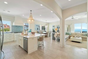 A spacious kitchen with an island, a dining area, and a living room with a view. - Vizcaya 1001 (Santa Rosa Beach)