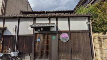 Um edifício japonês tradicional com entrada de madeira, uma bicicleta estacionada na frente e uma placa com caracteres japoneses.