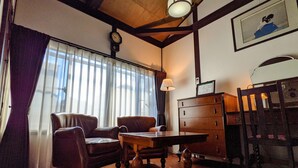 Habitació amb taula de fusta, dues cadires de pell, un armari de fusta i un rellotge a la paret.