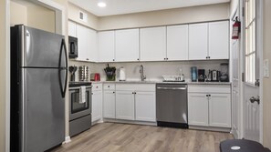 Una cocina moderna con armarios blancos, electrodomésticos de acero inoxidable y suelo de madera.