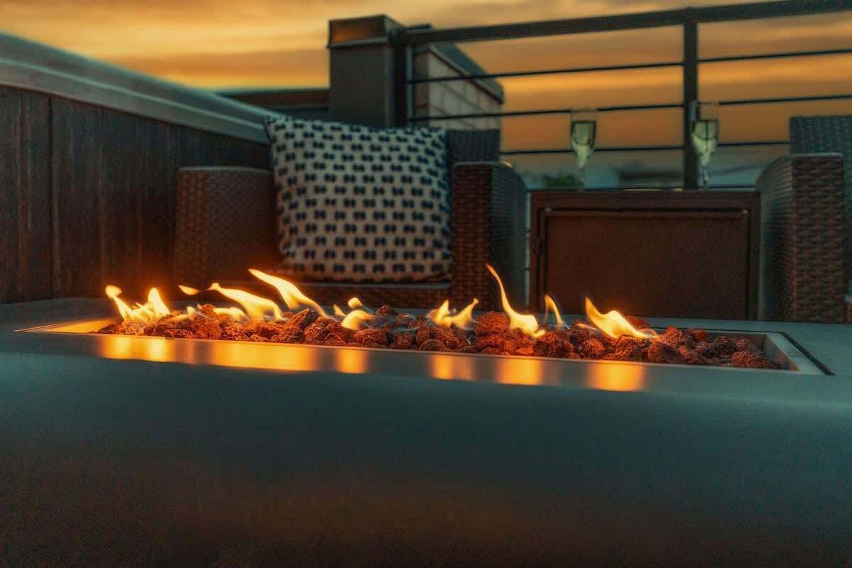 A modern living room with a built-in fireplace, a patterned throw pillow, and a glass-top coffee table.