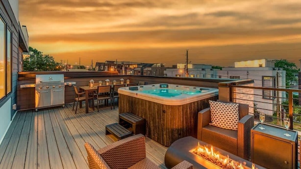 Una terraza en la azotea con jacuzzi, mobiliario exterior, una parrilla y una chimenea.