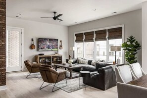 Un salón amplio con un sofá, sillas, una mesa de centro y un televisor.