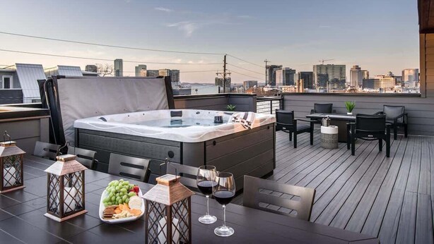 A rooftop terrace with a hot tub, dining table, chairs, and a city view. - Urban Row - Rooftop Hot Tub - Heart of Gulch (Nashville)