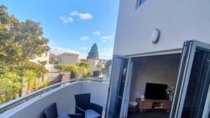Een balkon met rieten meubilair, een televisie en uitzicht op de omgeving.