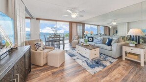 A spacious living room with a large window, a ceiling fan, and a dining area with a view.
