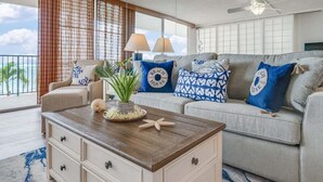 A living room with a sofa, a coffee table, and a view of the ocean.