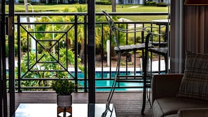 Ein Balkon mit Blick auf einen Pool, einem Glastisch, einem Stuhl und einer Couch.