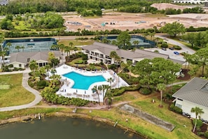 Resort com piscina, quadras de tênis e um edifício grande com várias varandas.