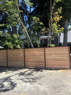 Surrounded by trees and a charming building, this property features a well-maintained outdoor space with a fence and gravel ground.