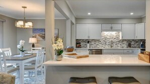 Una cocina moderna con gabinetes grises, una isla central y un salpicadero de piedra.